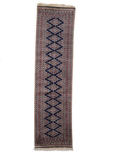 Vista frontal completa de una alfombra persa con diseño geométrico en tonos azul marino, beige y rojo.