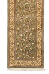Detalle inferior de la alfombra con énfasis en la guarda beige decorada con motivos florales.