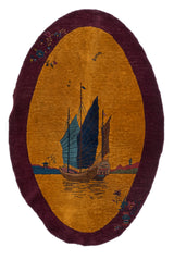 Vista completa de una alfombra ovalada con diseño de barco oriental sobre un fondo dorado y borde burdeos.