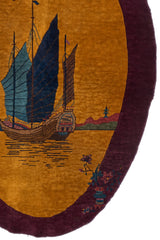 Detalle del barco tradicional con velas azul marino y marrón, sobre aguas doradas, con paisaje de fondo.