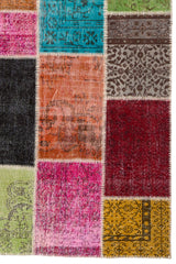 Detalle del lado derecho inferior de la alfombra patchwork con énfasis en los patrones florales en tonos rojos, naranjas y verdes.