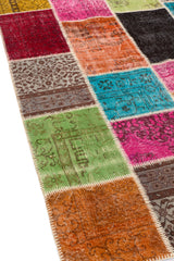 Vista en ángulo de la alfombra patchwork resaltando su textura y la variedad de colores como el verde, turquesa, rosa y gris.