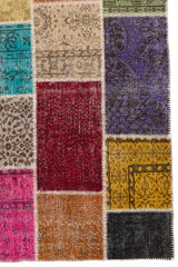Detalle de los cuadros laterales de la alfombra, donde se aprecian motivos florales sobre fondo morado, mostaza y rojo oscuro.