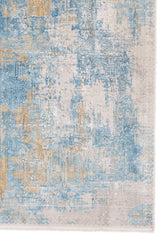 Detalle lateral de la alfombra mostrando su patrón abstracto en tonos azul, beige y dorado.