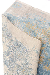 Parte trasera de la alfombra doblada, mostrando la base tejida y el reverso del diseño en azul y beige.