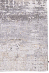 Detalle del diseño texturizado de la alfombra en tonos grises y beige, destacando su acabado artístico y elegante.