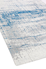 Perspectiva lateral de la alfombra que muestra la integración del diseño azul con las texturas en gris y blanco.