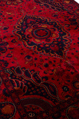 Vista lateral en perspectiva de la alfombra persa destacando el contraste vibrante entre los tonos rojos y los detalles oscuros.