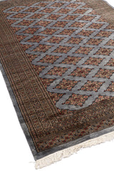 Vista lateral en perspectiva de la alfombra, resaltando la repetición simétrica del diseño y los tonos suaves del fondo gris.