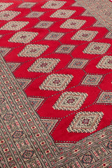 Vista lateral en profundidad de la alfombra oriental, resaltando los motivos geométricos tradicionales y el contraste cromático.