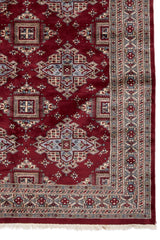 Detalle lateral de la alfombra que muestra el diseño geométrico en forma de diamante y la elaborada guarda con motivos florales.