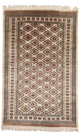 Vista superior completa de una alfombra artesanal con fondo marfil y patrón geométrico en tonos rojo y negro.
