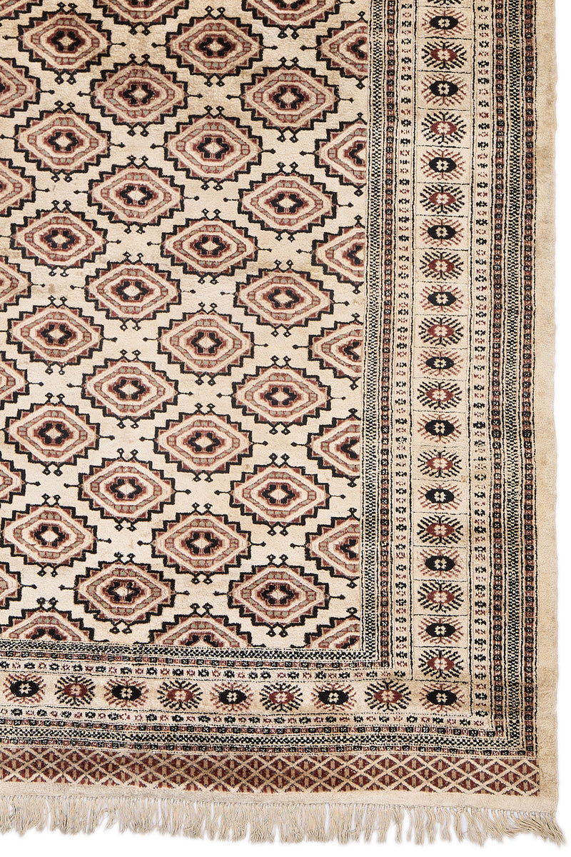 Detalle lateral de la alfombra mostrando el diseño de diamantes y el borde con motivos florales.