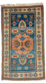 Vista superior completa de una alfombra tradicional con fondo azul y motivos geométricos en tonos terracota, verde y marfil.