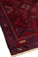 Vista en ángulo de alfombra oriental mostrando textura y borde decorado con motivos tribales.