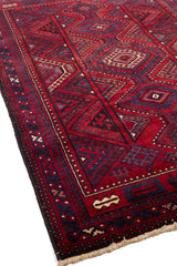 Perspectiva lateral de alfombra oriental destacando figuras geométricas en tonos rojo, azul y negro