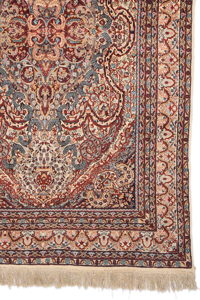 Detalle del borde derecho inferior de la alfombra, mostrando los intrincados motivos florales en tonos marfil, terracota, celeste y burdeos sobre fondo beige claro.