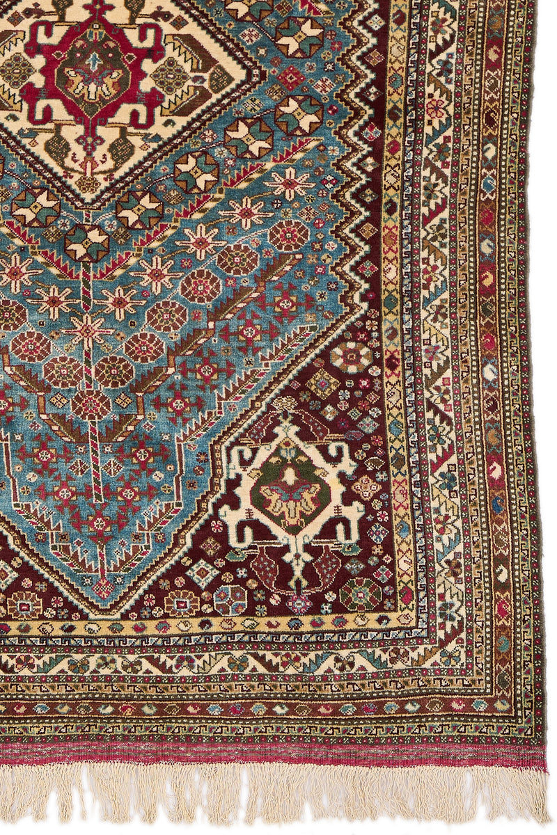 Detalle del borde derecho de la alfombra mostrando la guardilla en tonos marfil, verde oliva, burdeos y azul claro con patrones florales y geométricos.