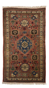 Vista completa de una alfombra oriental con fondo terracota, medallones azul marino y detalles en marfil, verde musgo y negro.