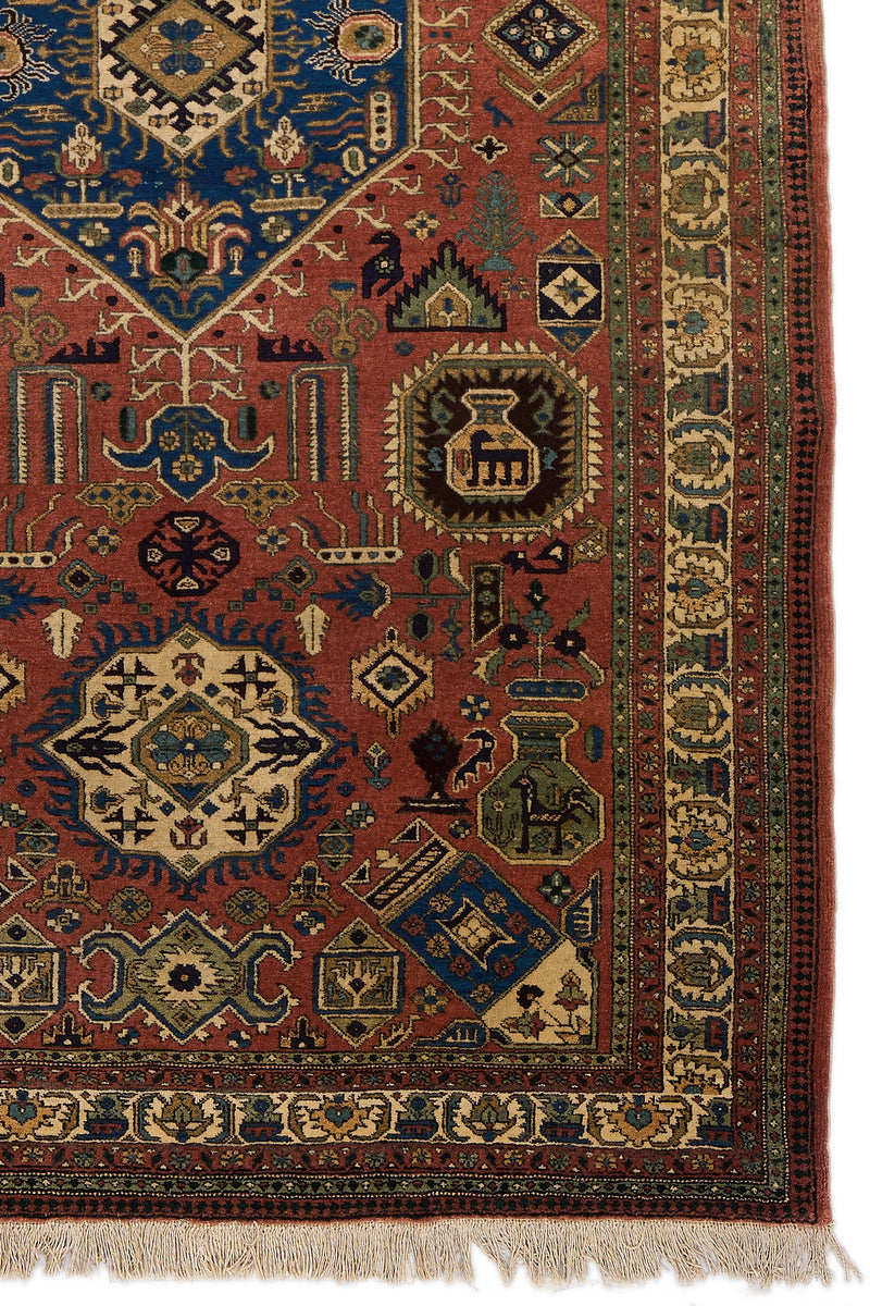 Detalle del borde derecho de la alfombra, donde se destacan los motivos geométricos en tonos crema y azul sobre fondo rojo.