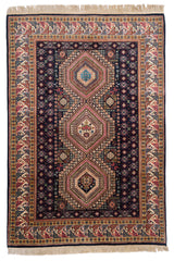 Vista completa de alfombra oriental con fondo azul oscuro, tres medallones geométricos centrales y bordes beige con patrones tribales.
