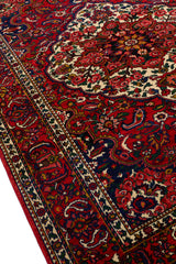 Vista en ángulo de la alfombra resaltando la textura y el diseño floral central con predominio del rojo y marfil.
