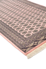 Alfombra de diseño en tonos rosados con patrones geométricos tradicionales y detalles en negro.