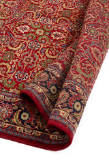Detalle enrollado de alfombra verde con diseño floral y borde beige.