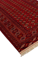Alfombra oriental extendida, mostrando su intrincado patrón geométrico en tonos rojos.