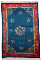 Alfombra oriental con fondo azul y detalles florales en las esquinas.