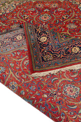Detalle de una alfombra persa clásica con intrincados patrones florales sobre un fondo rojo vibrante y ribetes en tonos azules y crema.