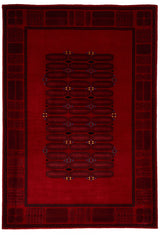 Primer plano de una alfombra roja con detalles geométricos oscuros y toques de color amarillo y azul.