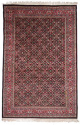 Vista completa de la alfombra persa con detalles florales en tonos rojos y negros.