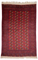 Alfombra oriental con fondo rojo y patrones geométricos en tonos beige y negro, mostrando un diseño detallado y simétrico.