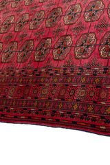 Vista cercana del borde de la alfombra, destacando los detalles de los patrones geométricos y florales en tonos contrastantes.