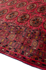 Esquina de la alfombra mostrando la textura y los detalles del borde, con el patrón floral y los flecos visibles.