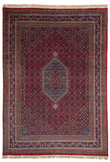 Vista completa de una alfombra persa con un diseño geométrico intrincado y patrones florales, en tonos predominantemente rojos y azules.