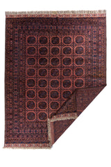 Alfombra parcialmente doblada mostrando reverso tejido y flecos artesanales en tono beige.