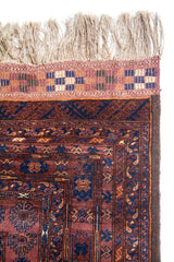 Detalle de flecos y borde superior de alfombra oriental con guarda geométrica en tonos beige y azul oscuro.