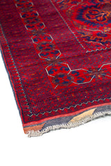 Detalle del diseño central de alfombra roja con medallones simétricos y patrones tribales.