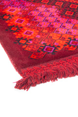 Detalle de guarda geométrica en alfombra roja con motivos lineales y acabado con flecos.