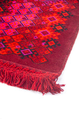 Borde lateral de alfombra artesanal roja con flecos tejidos a mano y patrones geométricos tradicionales.