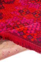 Textura de alfombra oriental roja con mosaico geométrico en tonos rosados y anaranjados.