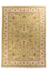 Alfombra clásica beige con diseño floral central y guarda decorativa en tonos verdes y rojo.