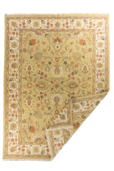 Alfombra tradicional beige con motivos florales y detalle de esquina doblada que muestra su reverso.