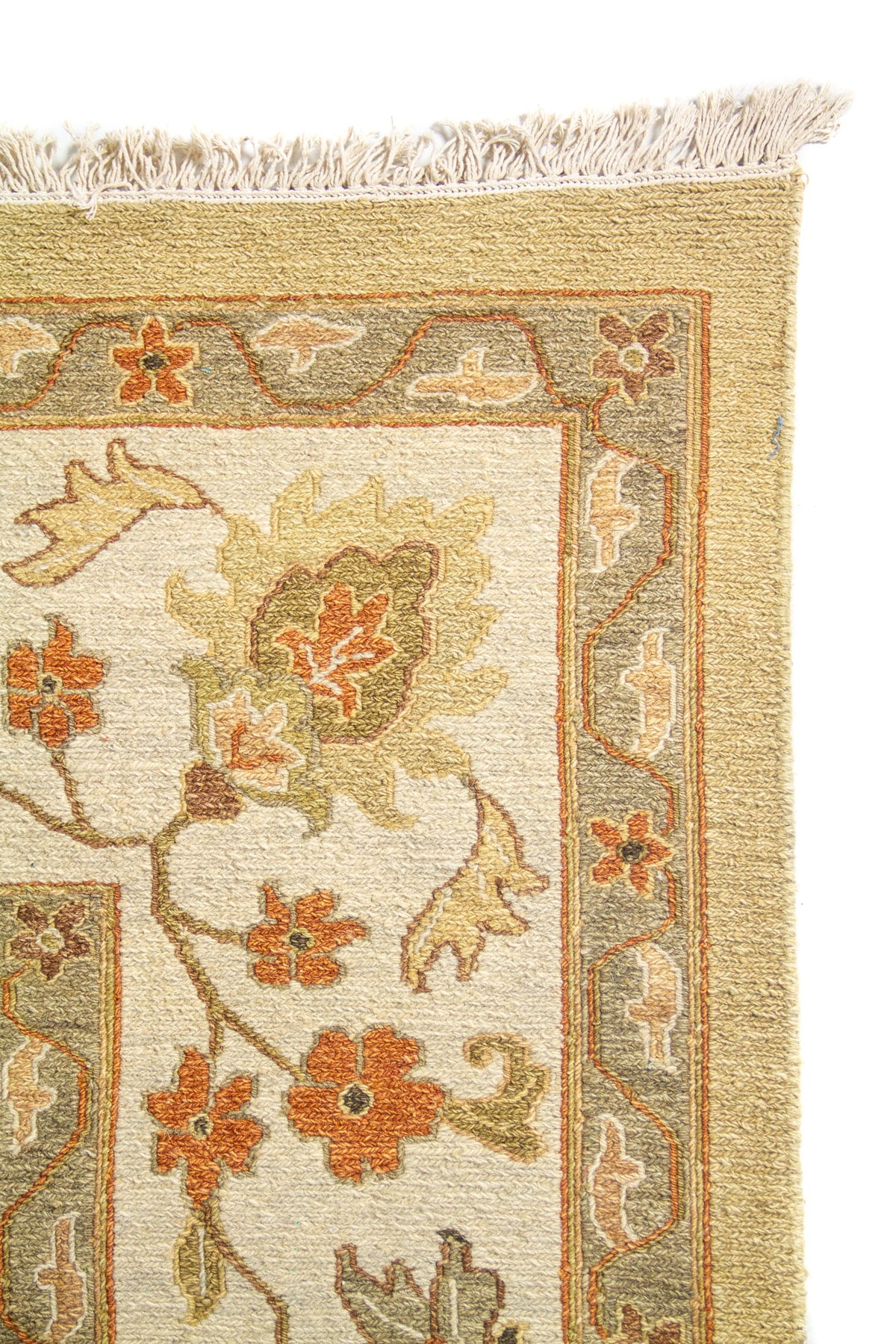 Detalle de guarda floral en alfombra beige con flores en tonos rojo, verde y beige.