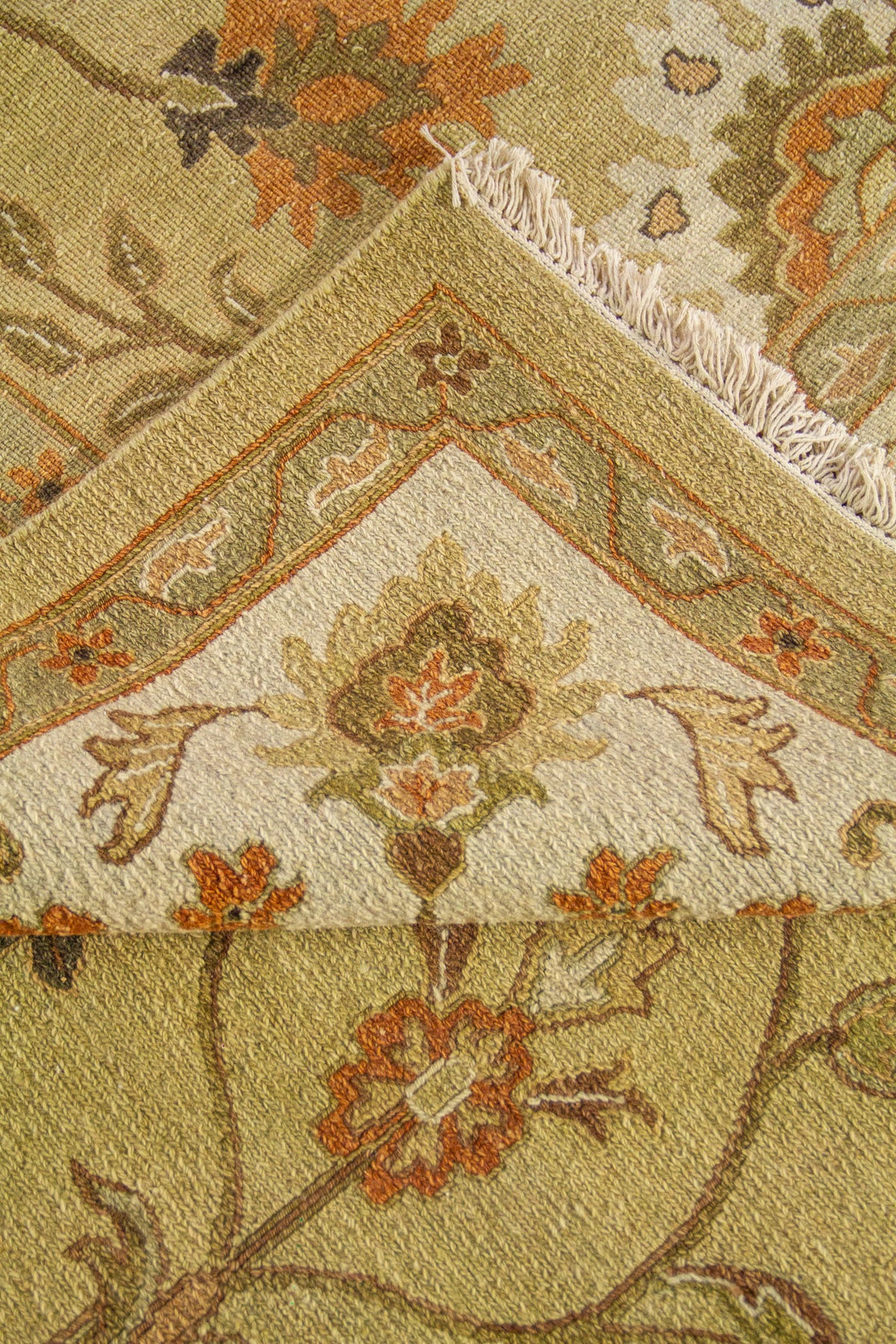 Detalle decorativo de alfombra beige con patrón floral simétrico y acabado artesanal.