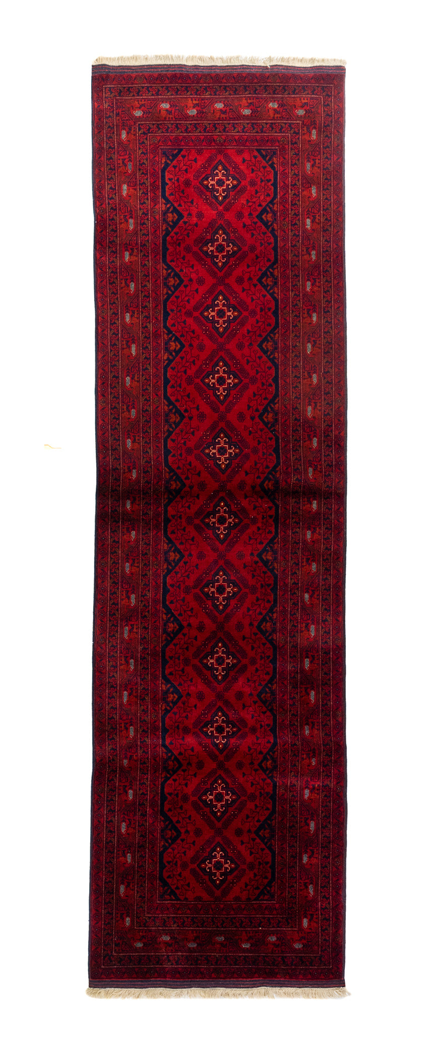 Alfombra estilo oriental de pasillo en tonos rojos profundos, con diseño geométrico central, bordes decorativos y flecos claros en los extremos.