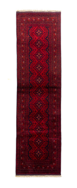 Alfombra estilo oriental de pasillo en tonos rojos profundos, con diseño geométrico central, bordes decorativos y flecos claros en los extremos.