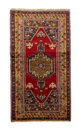 Alfombra rectangular en rojo y azul con diseño geométrico central y bordes ornamentales tradicionales